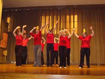Grupa taneczna w czerwono-czarnych strojach występująca na scenie